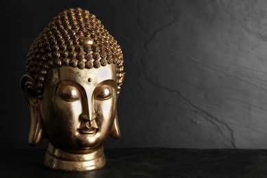 Buddha statue on black table against dark background, space for text