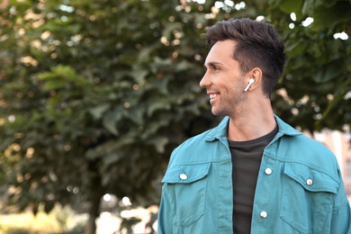 Photo of Young man with wireless earphones in park