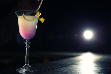 Photo of Glass of cosmopolitan martini cocktail on bar counter. Space for text