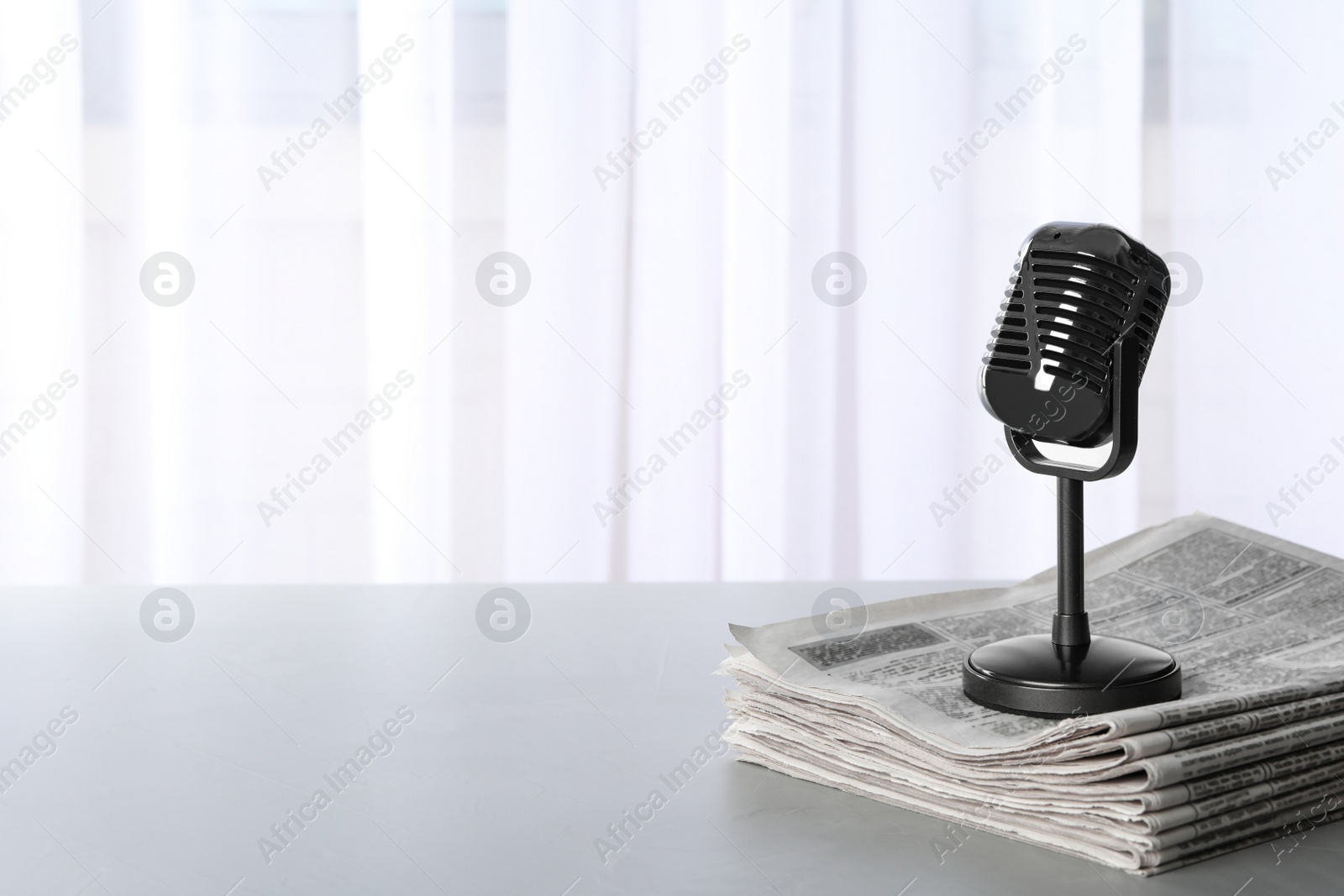 Photo of Newspapers and vintage microphone on grey table, space for text. Journalist's work