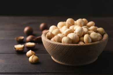 Photo of Bowl with shelled organic Macadamia nuts on wooden table. Space for text