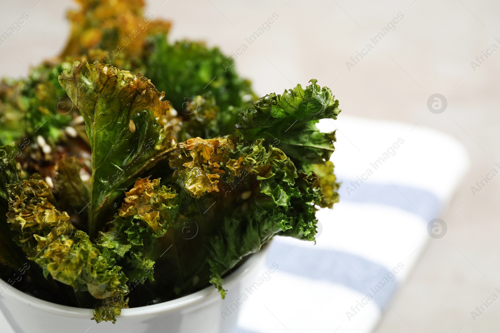 Photo of Tasty baked kale chips in bowl, closeup