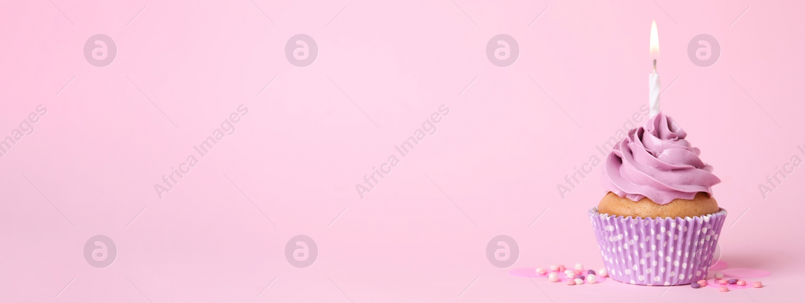 Image of Delicious birthday cupcake with burning candle and sprinkles on pink background, space for text. Banner design