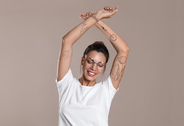 Image of Attractive woman with beautiful tattoo sketches on beige background