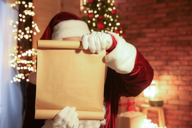 Photo of Santa Claus with blank wish list indoors
