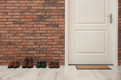 Photo of Different shoes near red brick wall in hallway