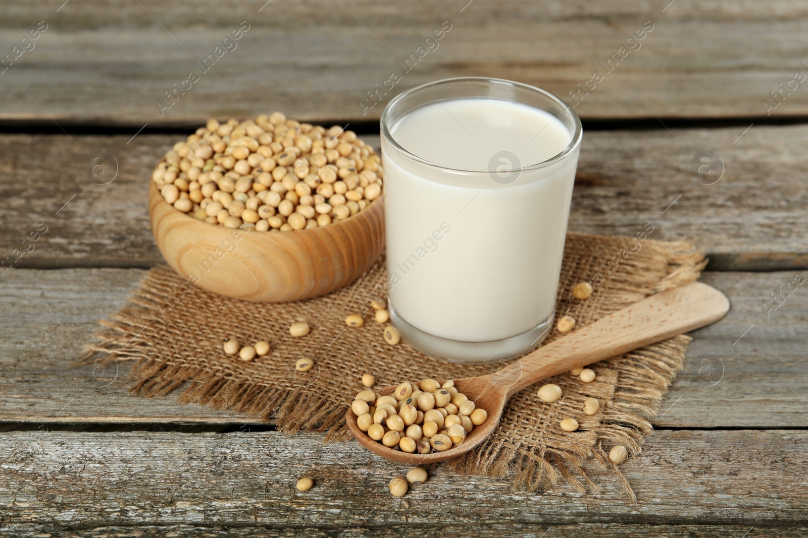 Photo of Glass with fresh soy milk and grains on wooden table