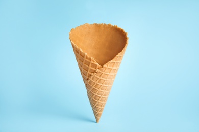 Photo of Empty wafer ice cream cone on blue background