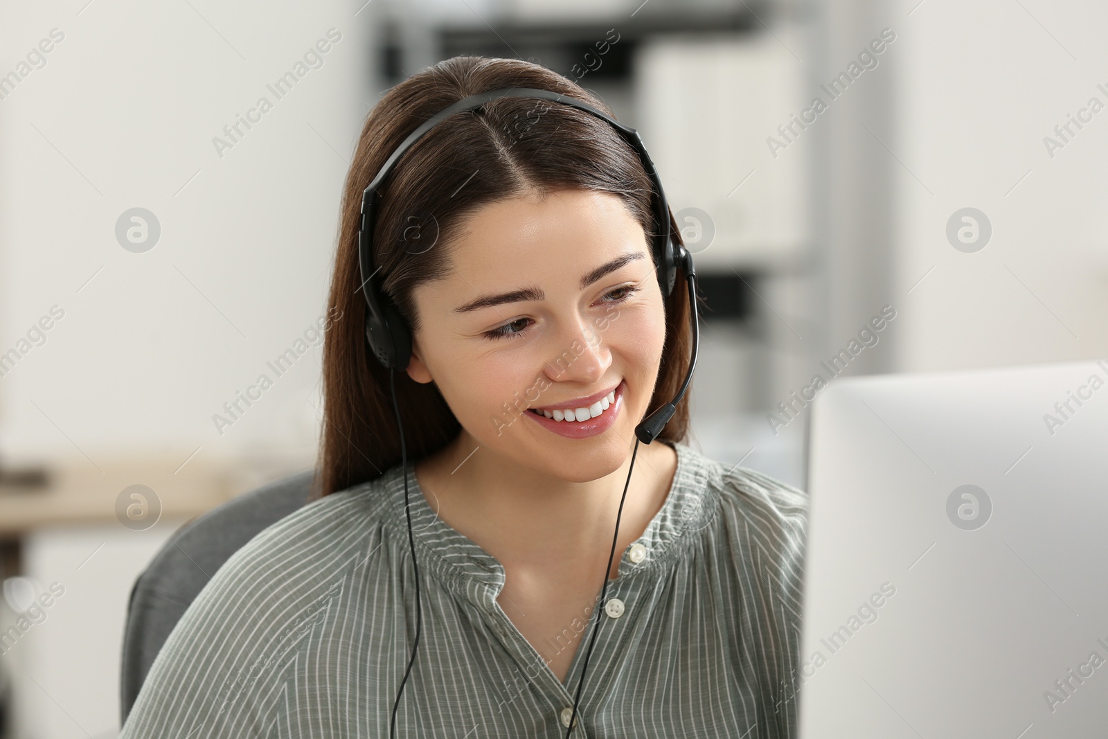 Photo of Hotline operator with headset working on computer in office