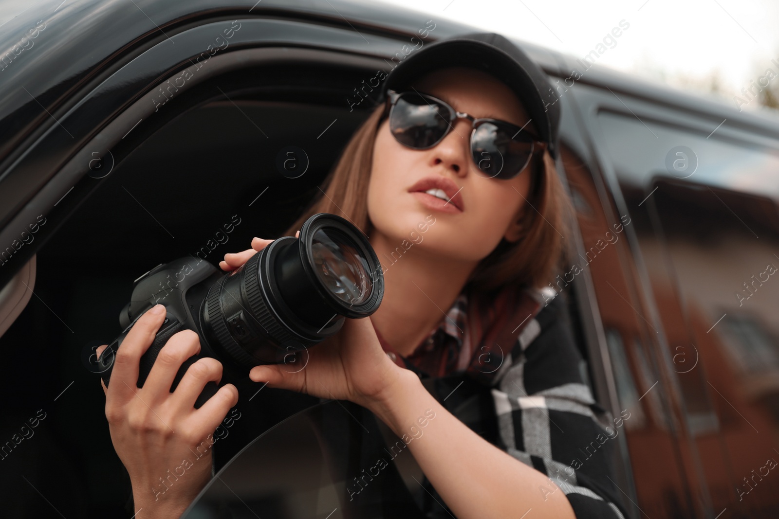 Photo of Private detective with camera spying from car