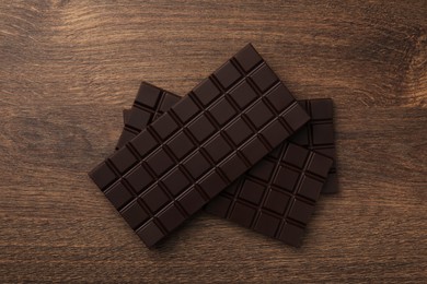 Photo of Tasty chocolate bars on wooden table, flat lay