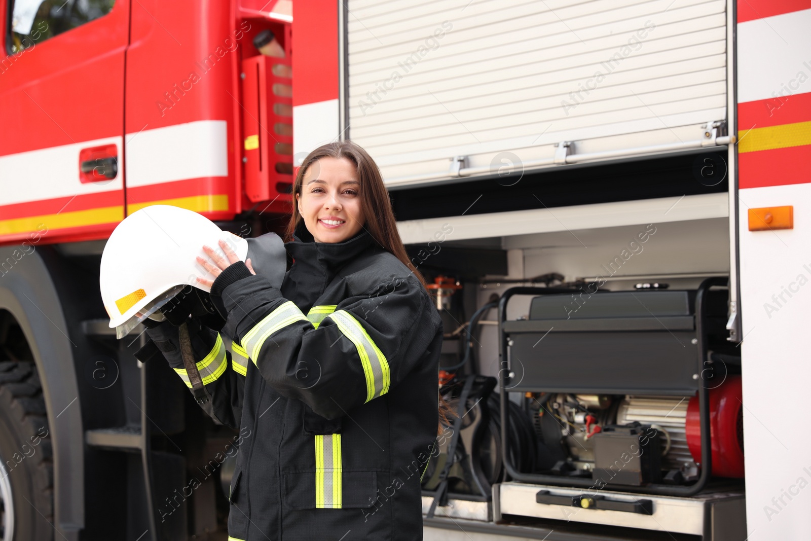 Photo of Portrait of firefighter in uniform with helmet near fire truck