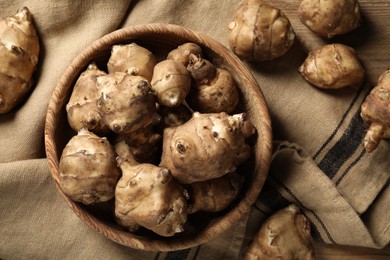 Fresh Jerusalem artichokes on brown cloth, flat lay