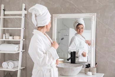 Photo of Beautiful woman looking at herself in bathroom mirror