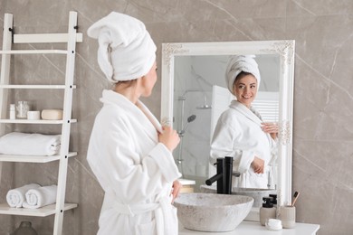 Beautiful woman looking at herself in bathroom mirror