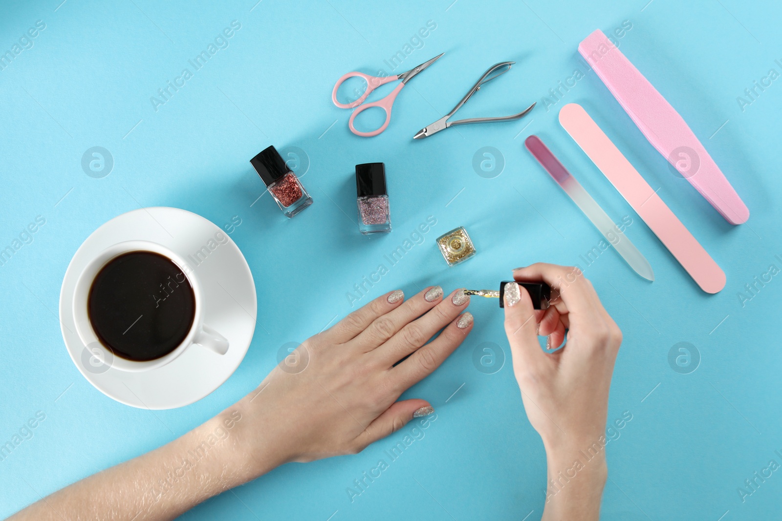 Photo of Woman applying nail polish on color background, top view