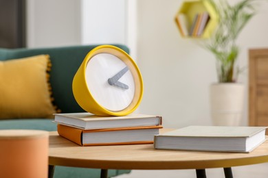 Spring atmosphere. Yellow clock and books on wooden table in living room