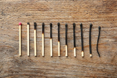 Row of burnt matches and whole one on wooden background, flat lay. Human life phases concept