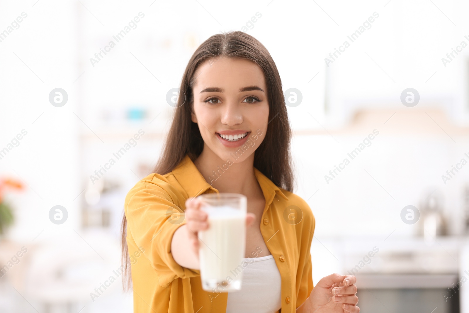 Photo of Beautiful young woman drinking milk at home