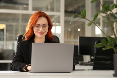 Photo of Woman working with laptop at white desk in office