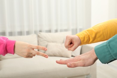 People playing rock, paper and scissors indoors, closeup