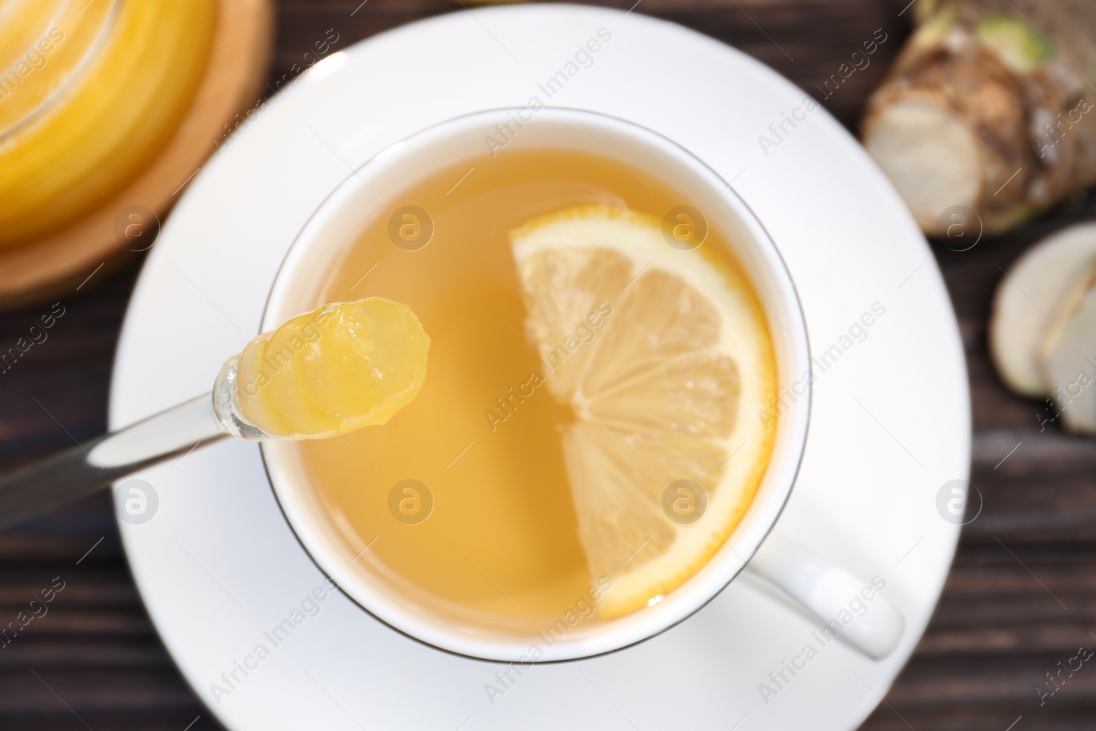 Photo of Cup of delicious tea with lemon and honey on wooden table, top view