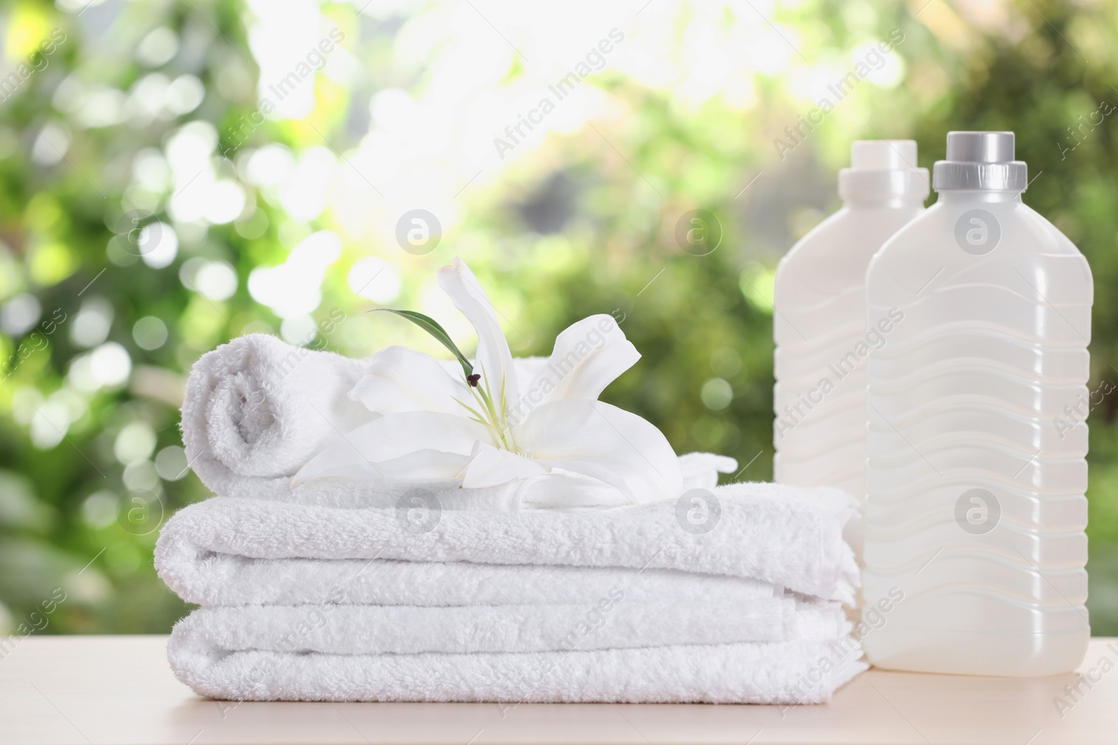 Photo of Soft bath towels and laundry detergents on table against blurred background