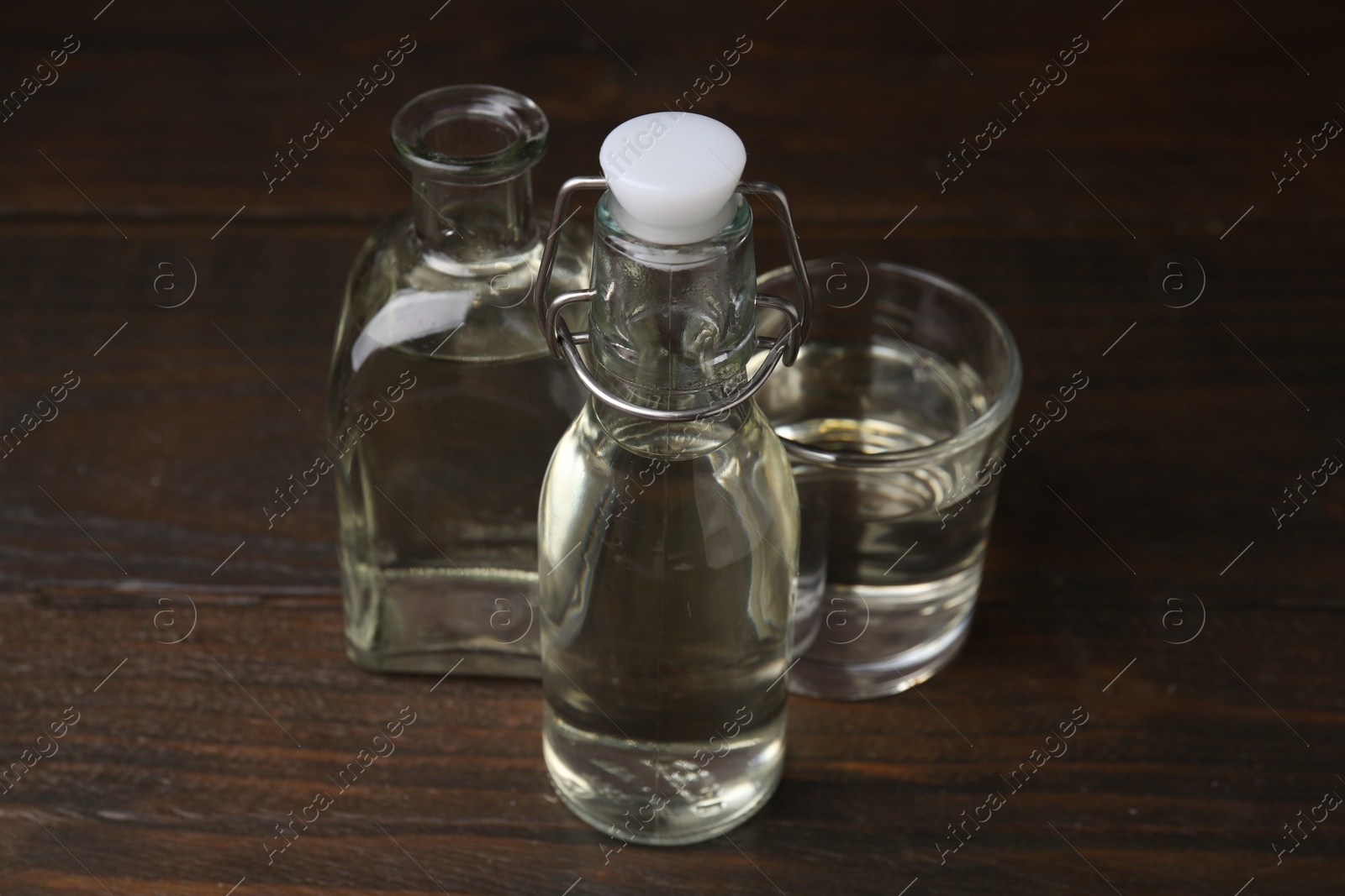 Photo of Vinegar in bottles and glass on wooden table