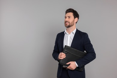 Happy real estate agent with leather portfolio on grey background. Space for text