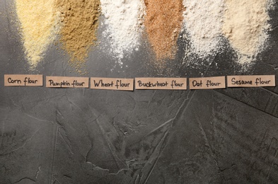 Photo of Stripes of different flour types and tags on grey table, top view. Space for text