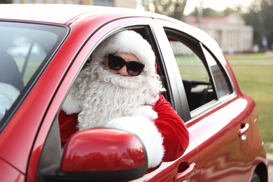 Authentic Santa Claus with sunglasses driving car, view from outside