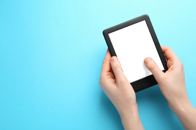 Woman using e-book reader on turquoise background, top view. Space for text
