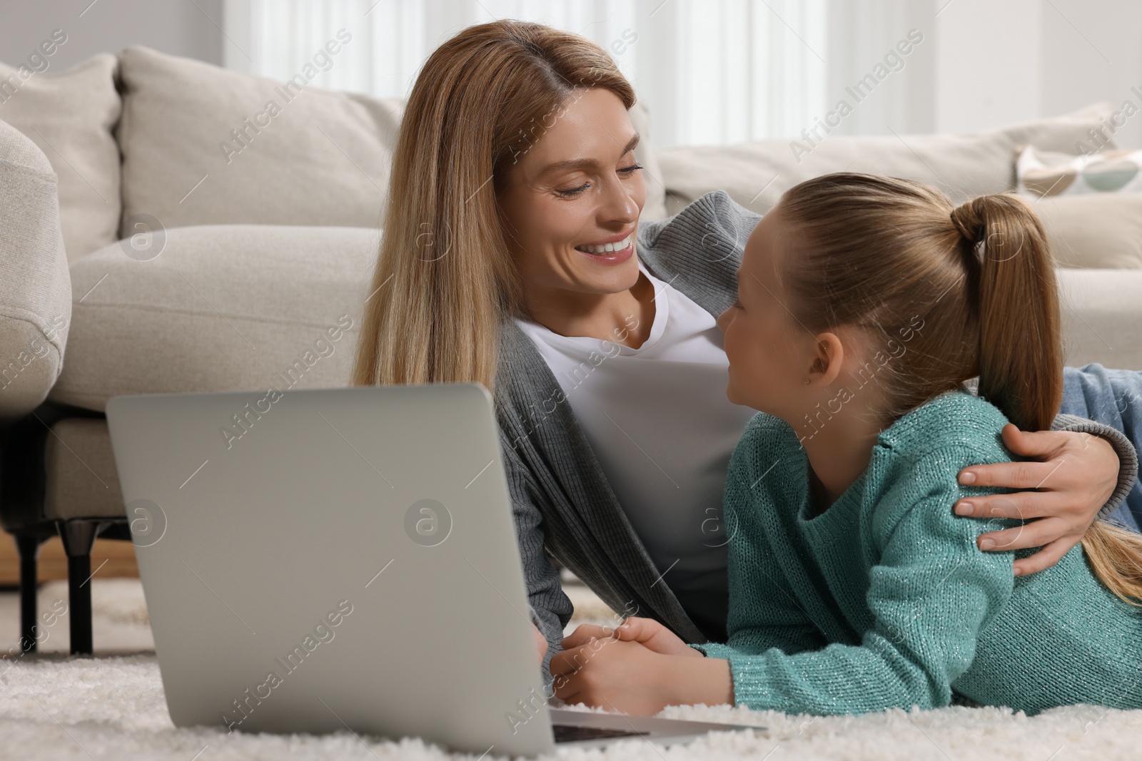 Photo of Happy woman and her daughter with laptop on floor at home