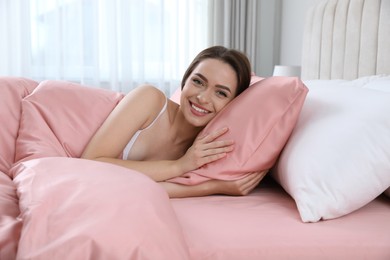 Photo of Young woman lying in comfortable bed with silky linens