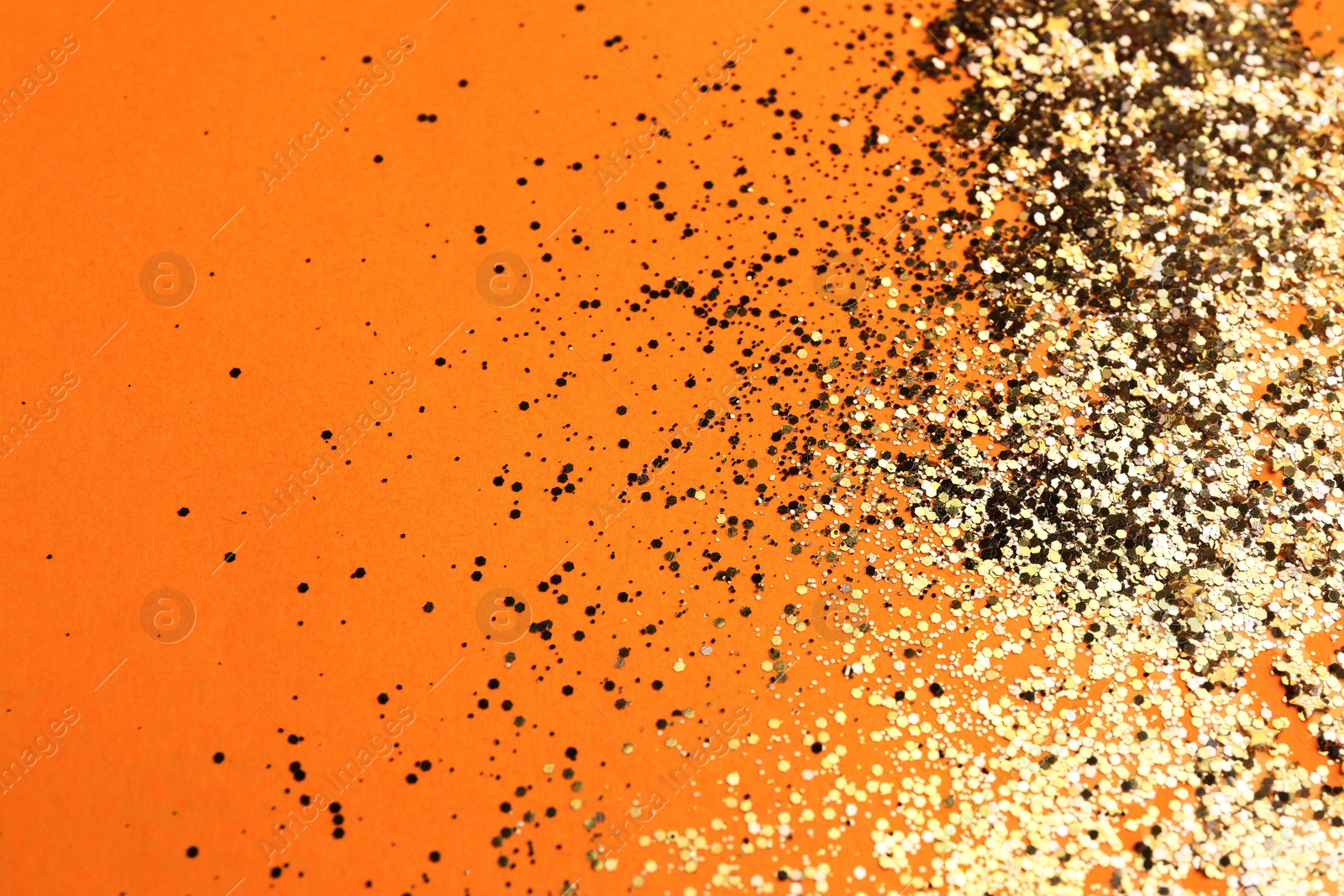 Photo of Shiny bright golden glitter on pale orange background. Space for text