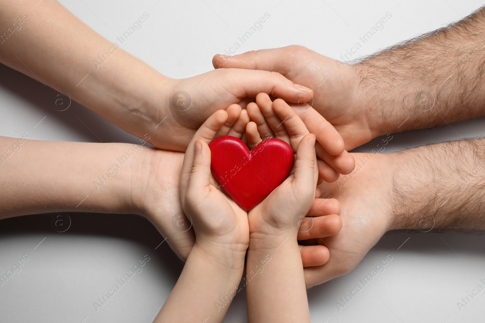 Photo of Parents and kid holding red heart in hands on light grey background, top view