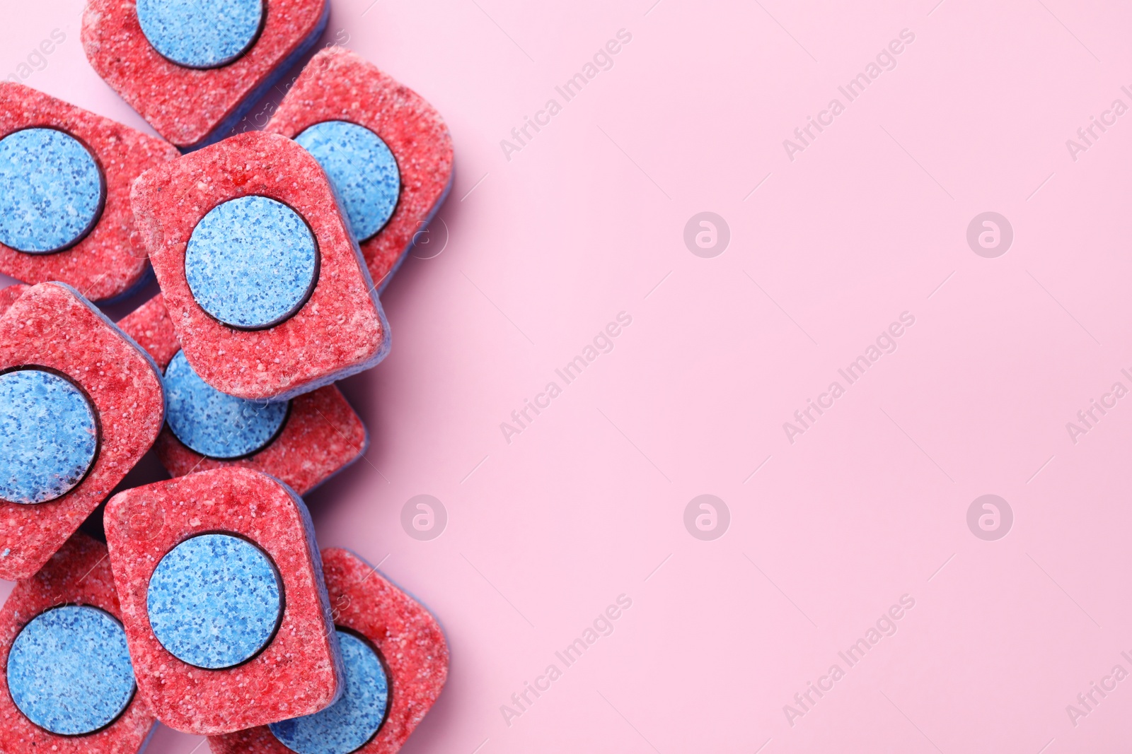 Photo of Many dishwasher detergent tablets on pink background, flat lay. Space for text