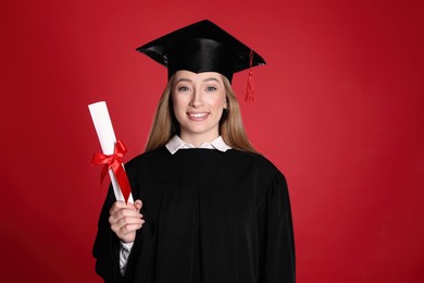 Happy student with diploma on red background