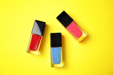 Photo of Bottles of nail polish on color background, top view