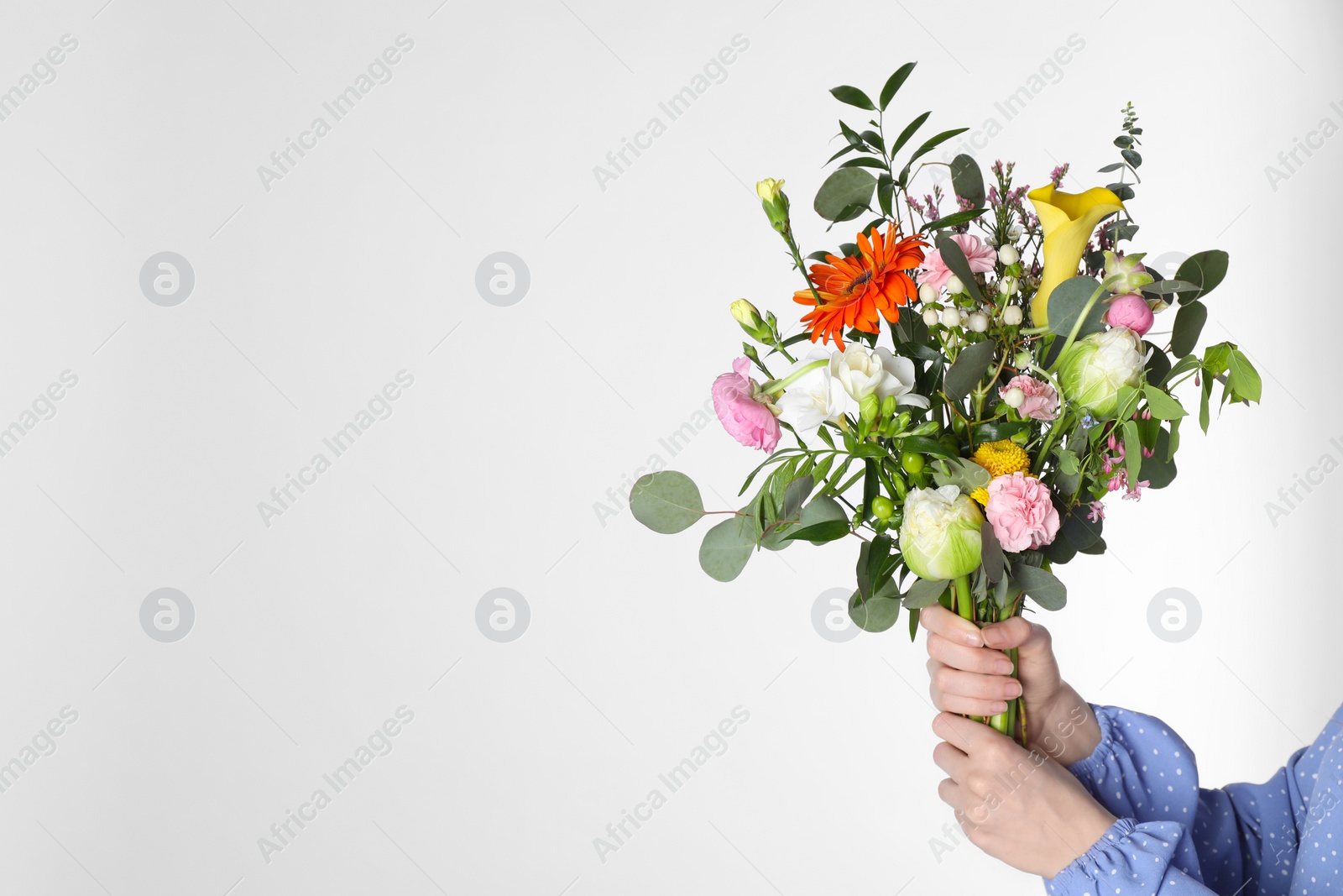 Photo of Woman with beautiful spring bouquet on light grey background, closeup and space for text