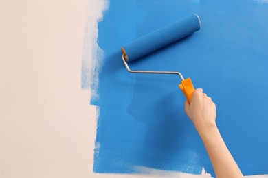 Photo of Woman painting wall with roller, closeup. Redecoration