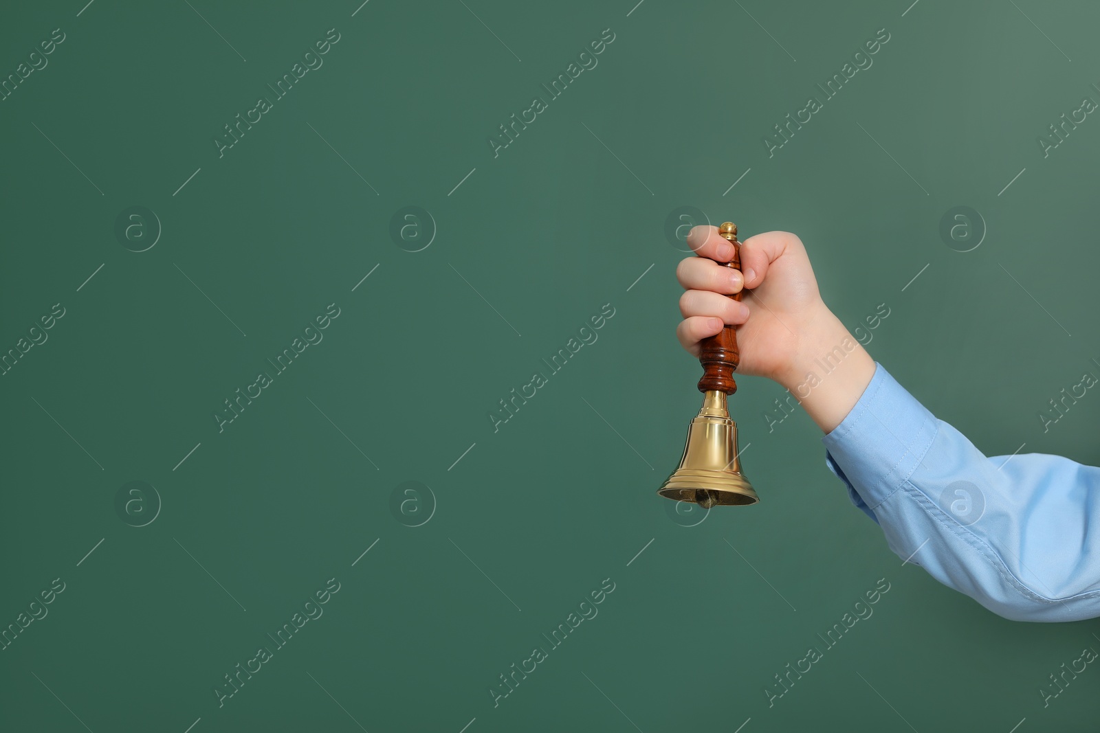 Photo of Pupil with school bell near green chalkboard, closeup. Space for text