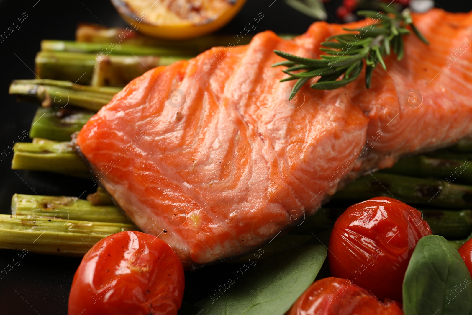 Photo of Tasty grilled salmon with tomatoes, asparagus and rosemary on plate, closeup