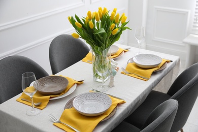 Beautiful Easter table setting with yellow tulips indoors