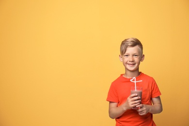 Little boy with glass of milk shake on color background