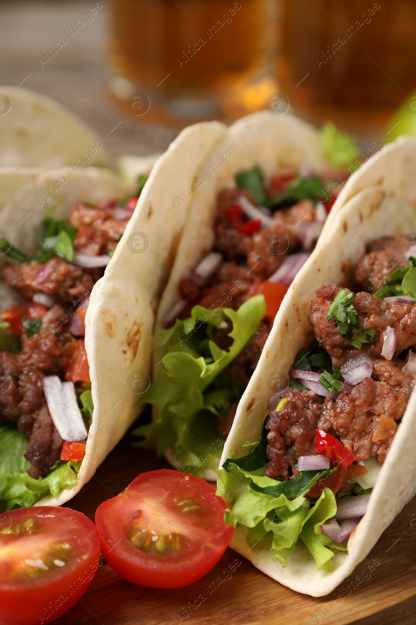 Photo of Delicious tacos with meat and vegetables on table, closeup