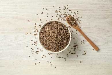 Photo of Ceramic bowl with chia seeds on light wooden table, flat lay. Cooking utensils