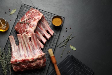 Photo of Raw ribs with thyme and pepper on black table, flat lay