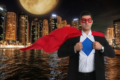 Businessman wearing superhero costume and beautiful cityscape in night on background