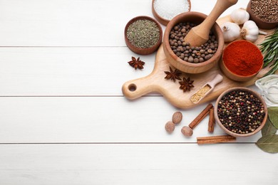 Mortar with pestle and different spices on white wooden table, flat lay. Space for text